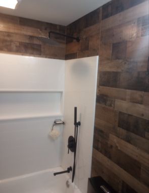 A bathroom with a bathtub, shower, and wooden walls