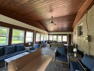 A screened in porch with a lot of furniture and a ceiling fan