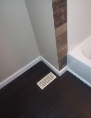 A bathroom with a bathtub and a vent on the floor