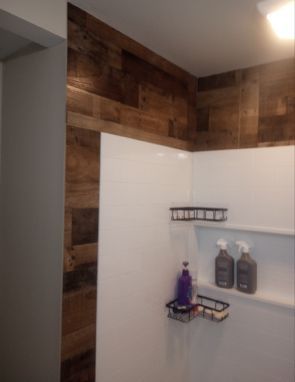 A bathroom with a shower stall and a shelf with bottles on it