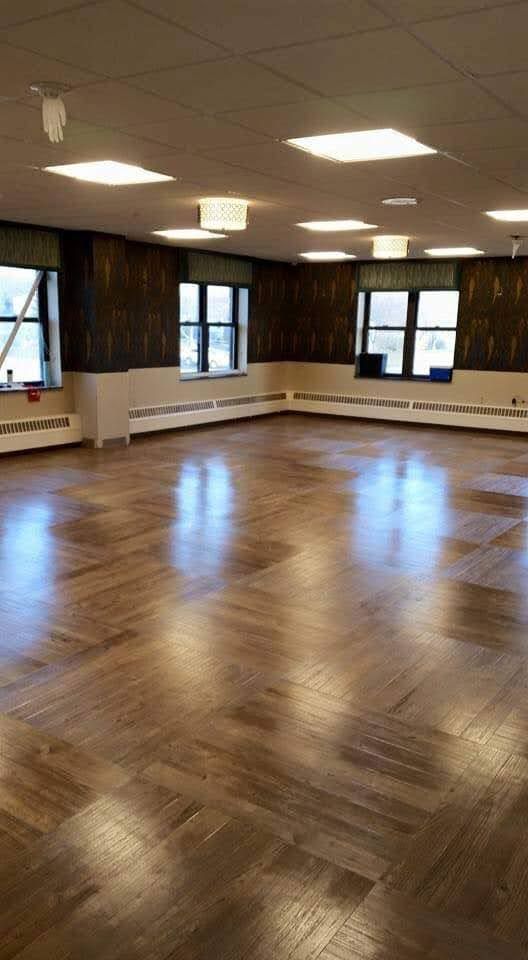 A large empty room with a wooden floor and windows