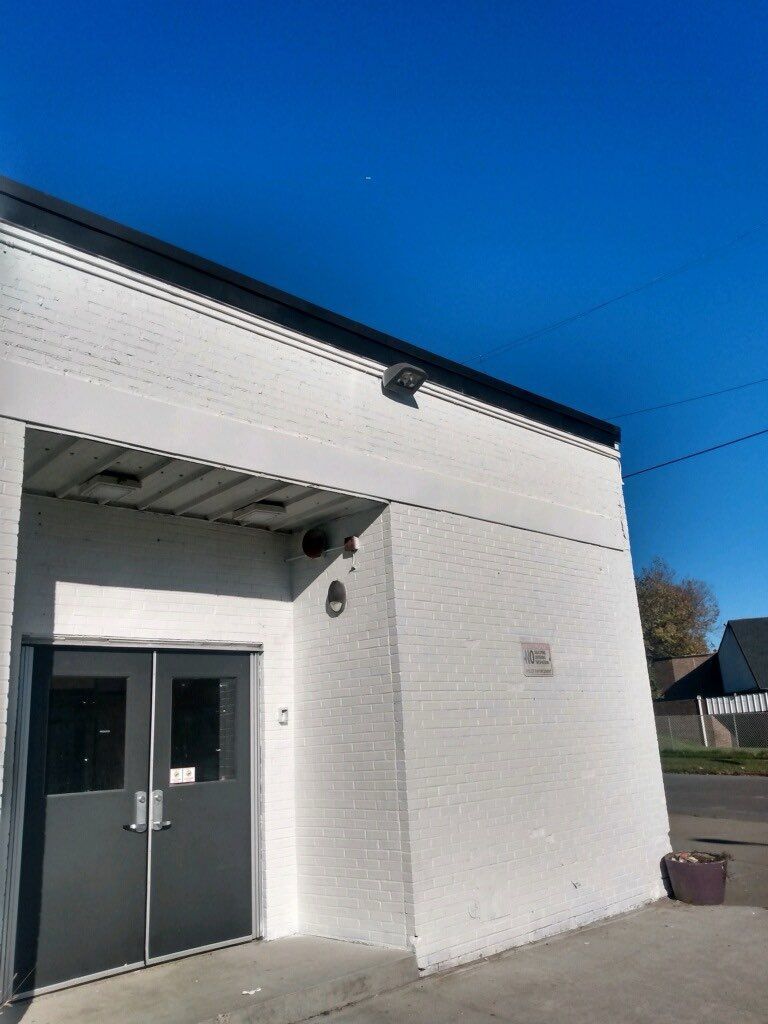 A white building with black doors and a blue sky in the background