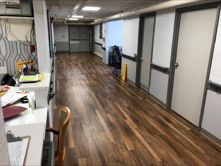 A long hallway with wooden floors and white doors in a hospital
