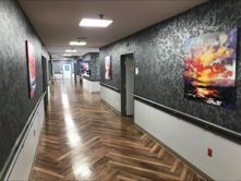 A long hallway with wooden floors and paintings on the walls