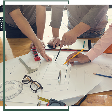 A group of people are sitting around a table looking at a blueprint.