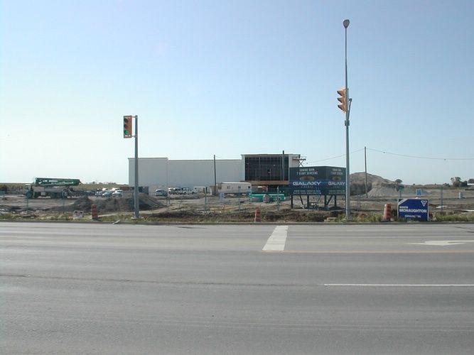 A large white building is being built on the side of the road