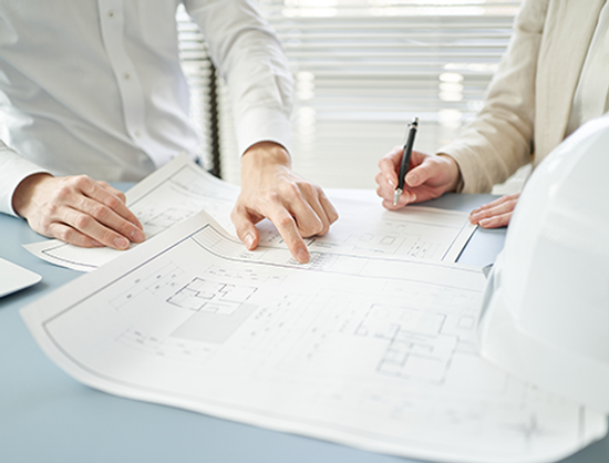 A man and a woman are sitting at a table looking at a blueprint.