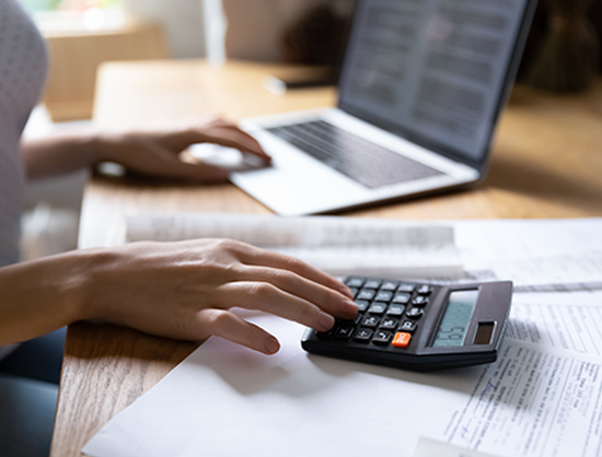 A person is using a laptop and a calculator at the same time.