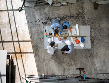 An aerial view of a group of people sitting around a table in a factory.
