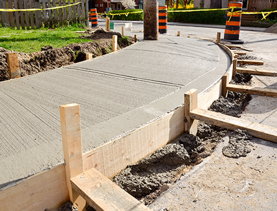 A concrete walkway is being built on the side of a road.