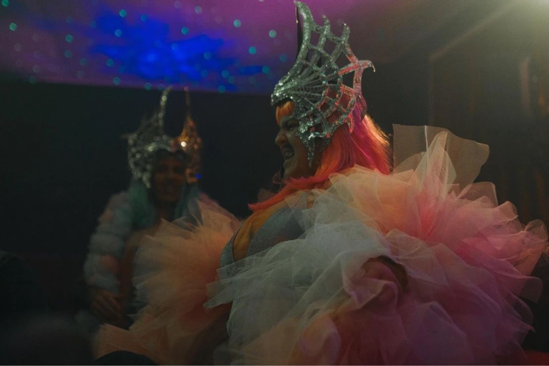 A woman in a pink dress and a crown is standing next to another woman in a pink dress — Lux Noir In  Townsville City, QLD