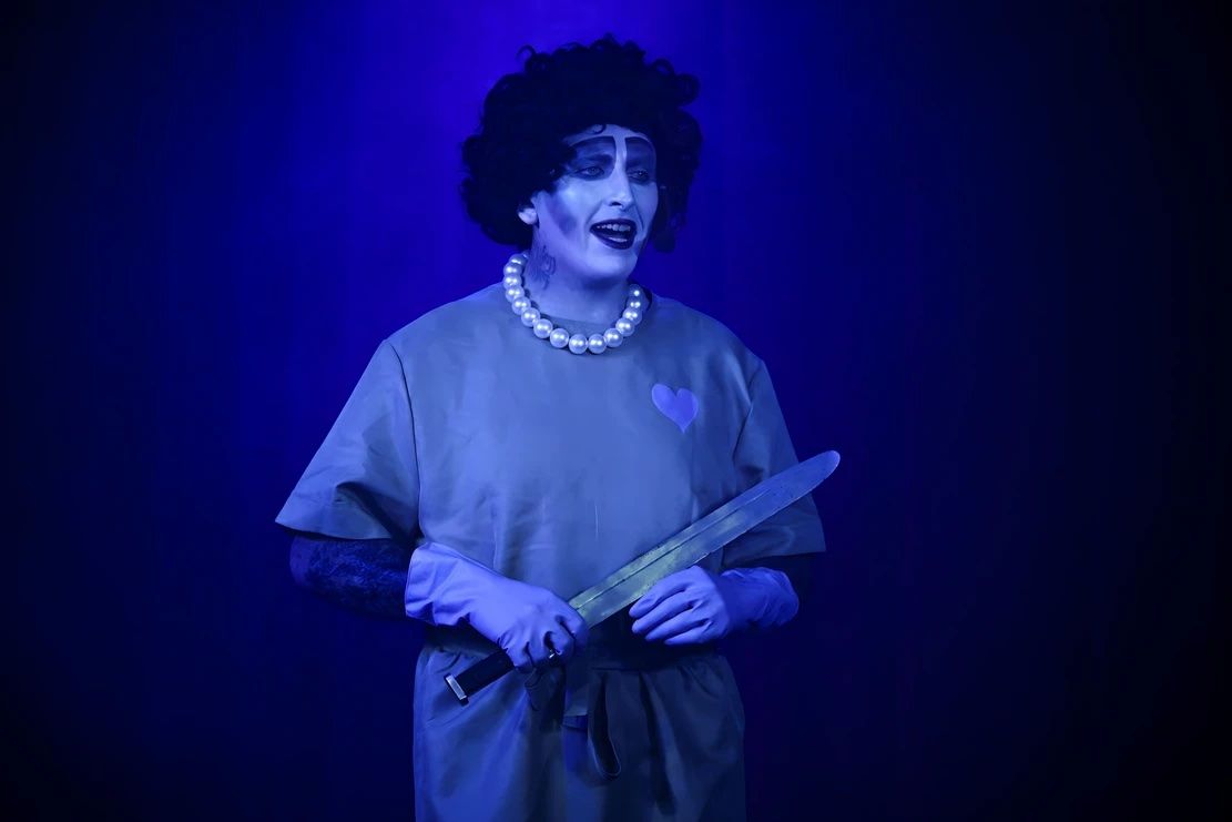 Performer in costume holding a knife under blue light — Lux Noir in Townsville City, QLD