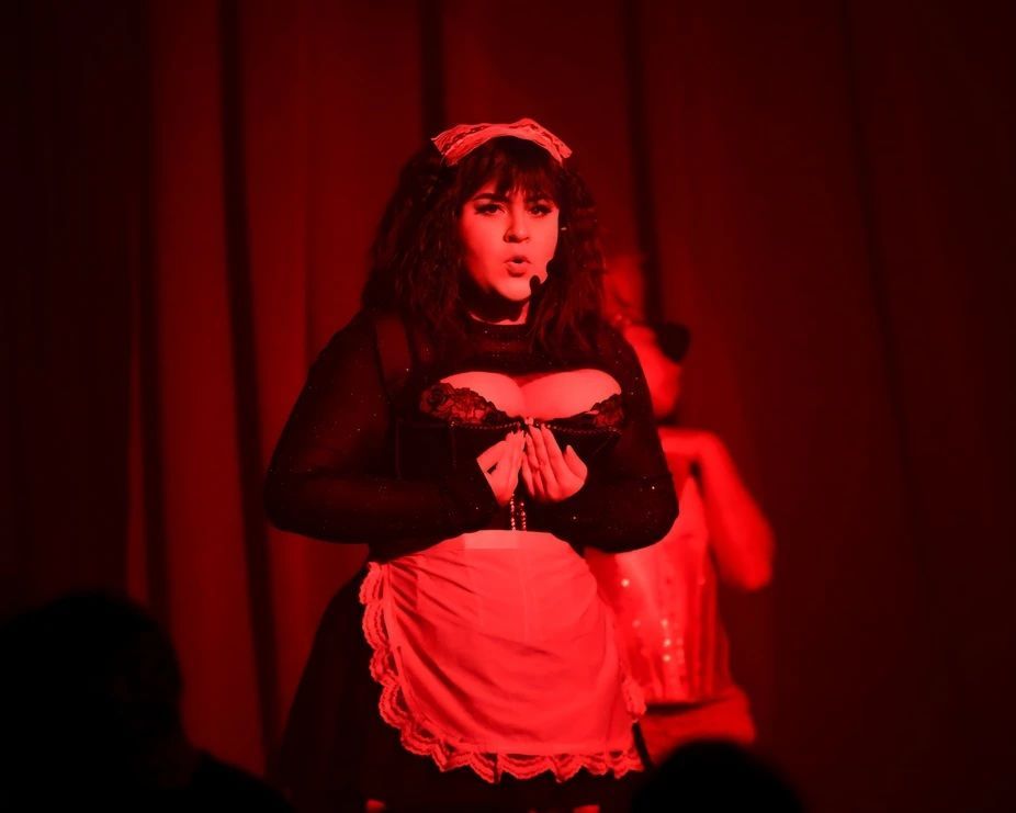 Performer in a maid costume under red stage lighting — Lux Noir in Townsville City, QLD