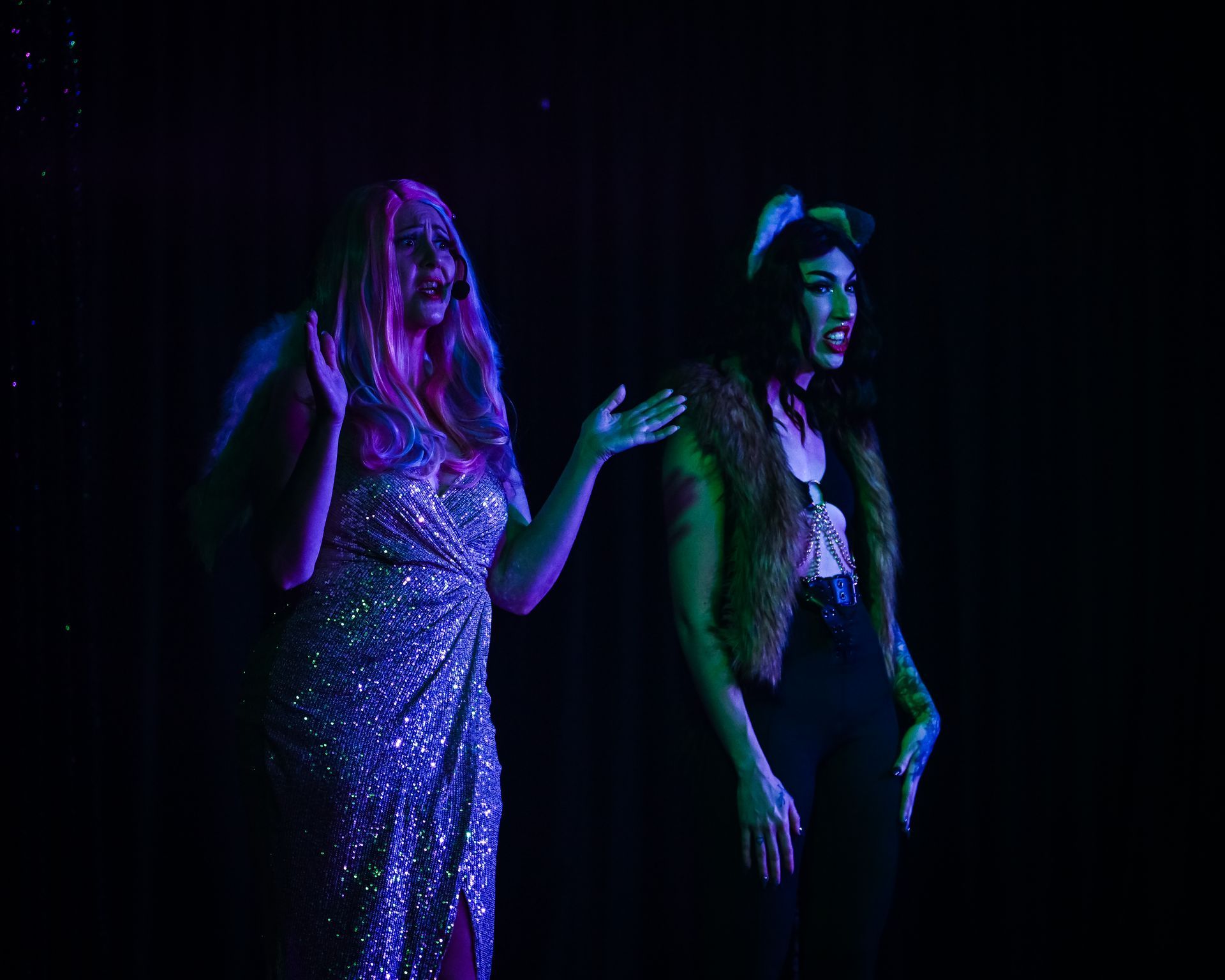 Two drag queens are standing next to each other on a stage in a dark room — Lux Noir in Townsville City, QLD