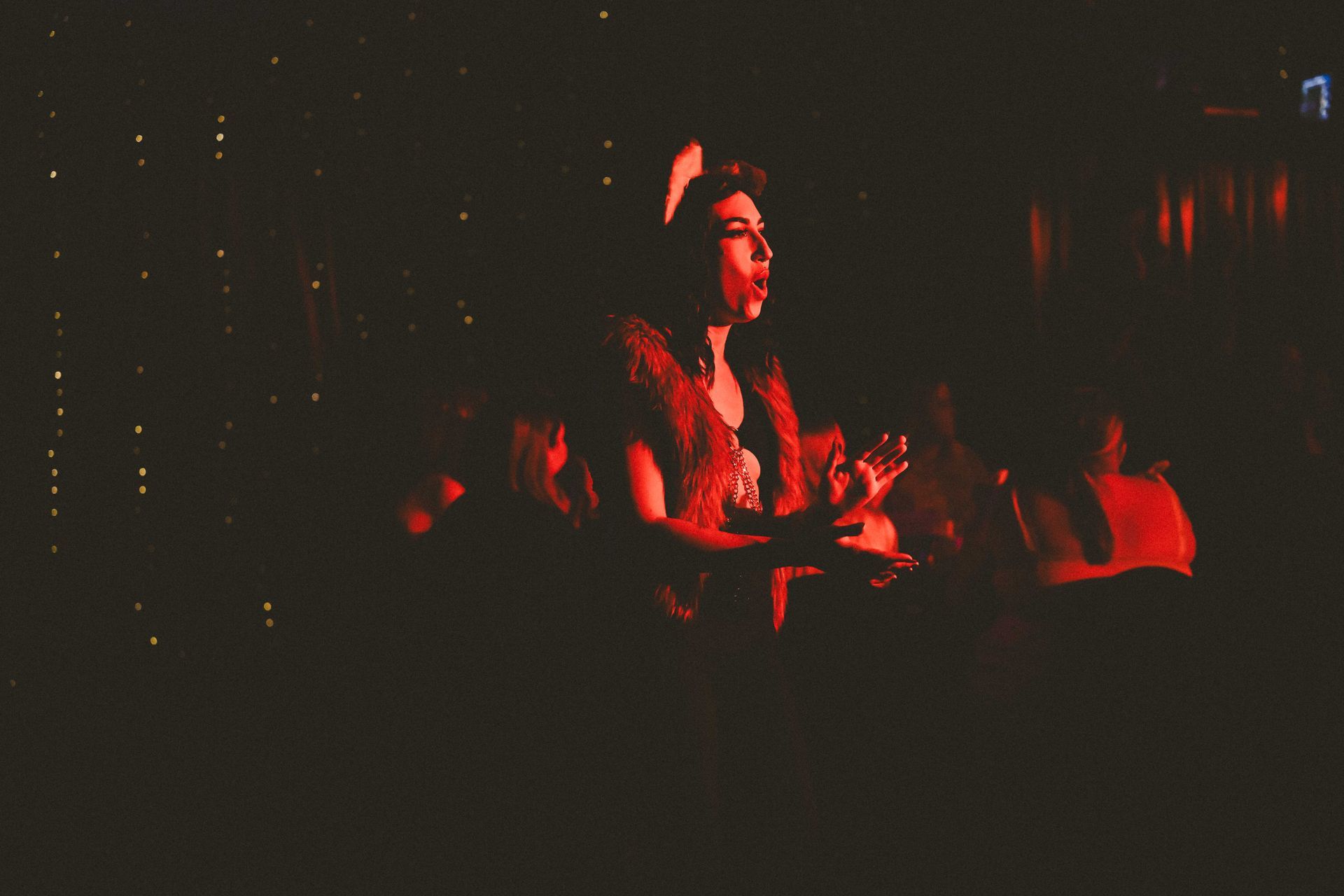A woman is singing into a microphone in a dark room— Lux Noir in Townsville City, QLD