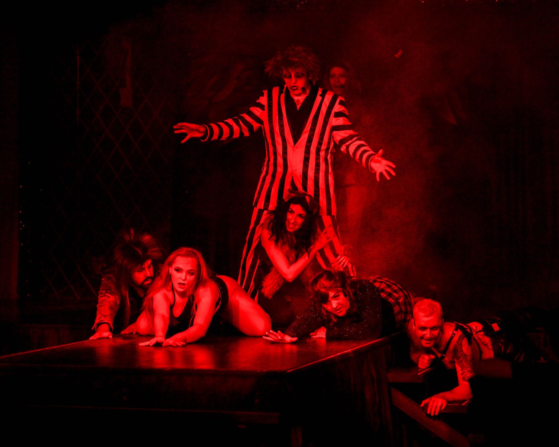 A group of people are dancing on a stage in a dark room with red lights — Lux Noir in Townsville City, QLD