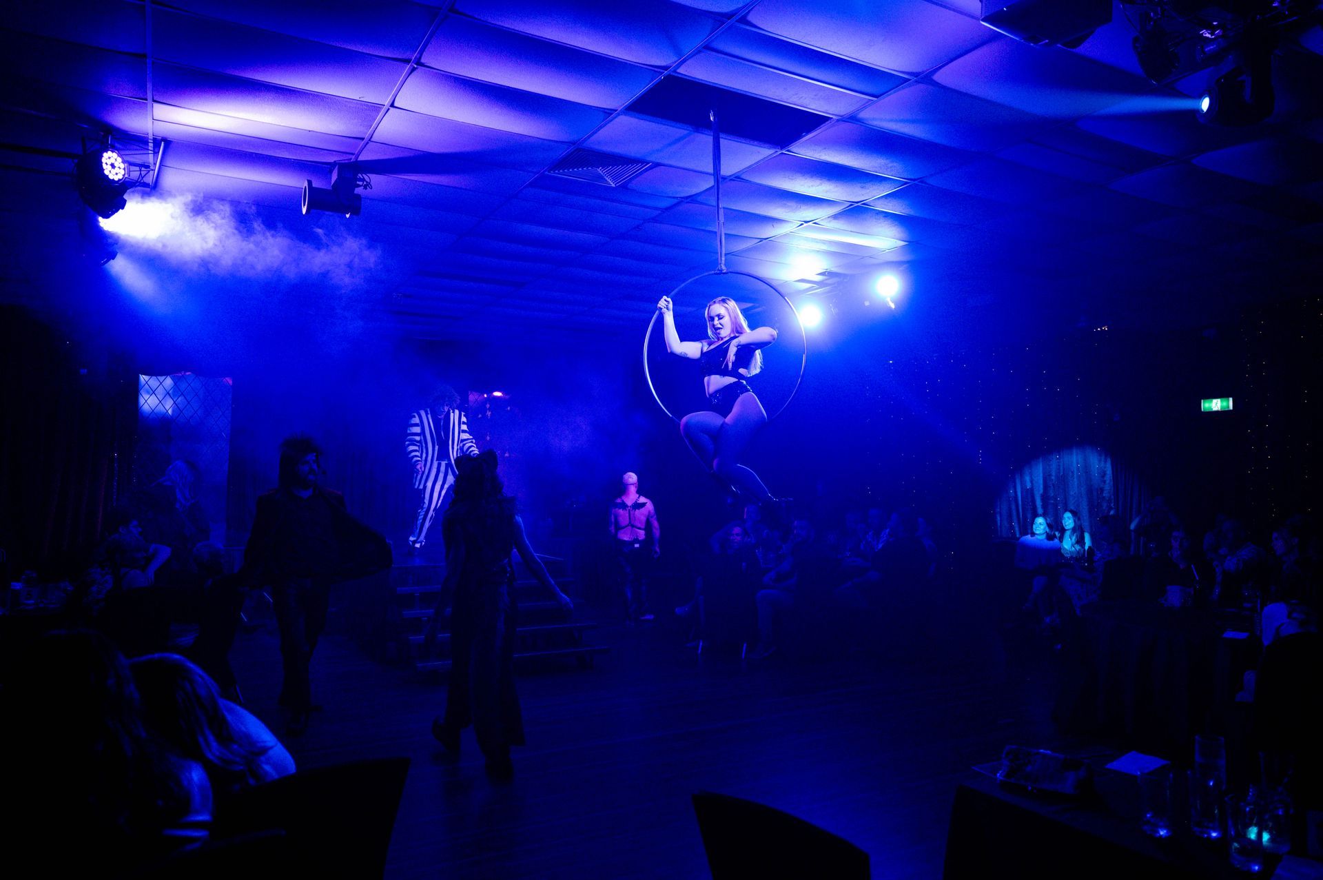 A woman is flying through the air in an aerial hoop in a dark room — Lux Noir in Townsville City, QLD