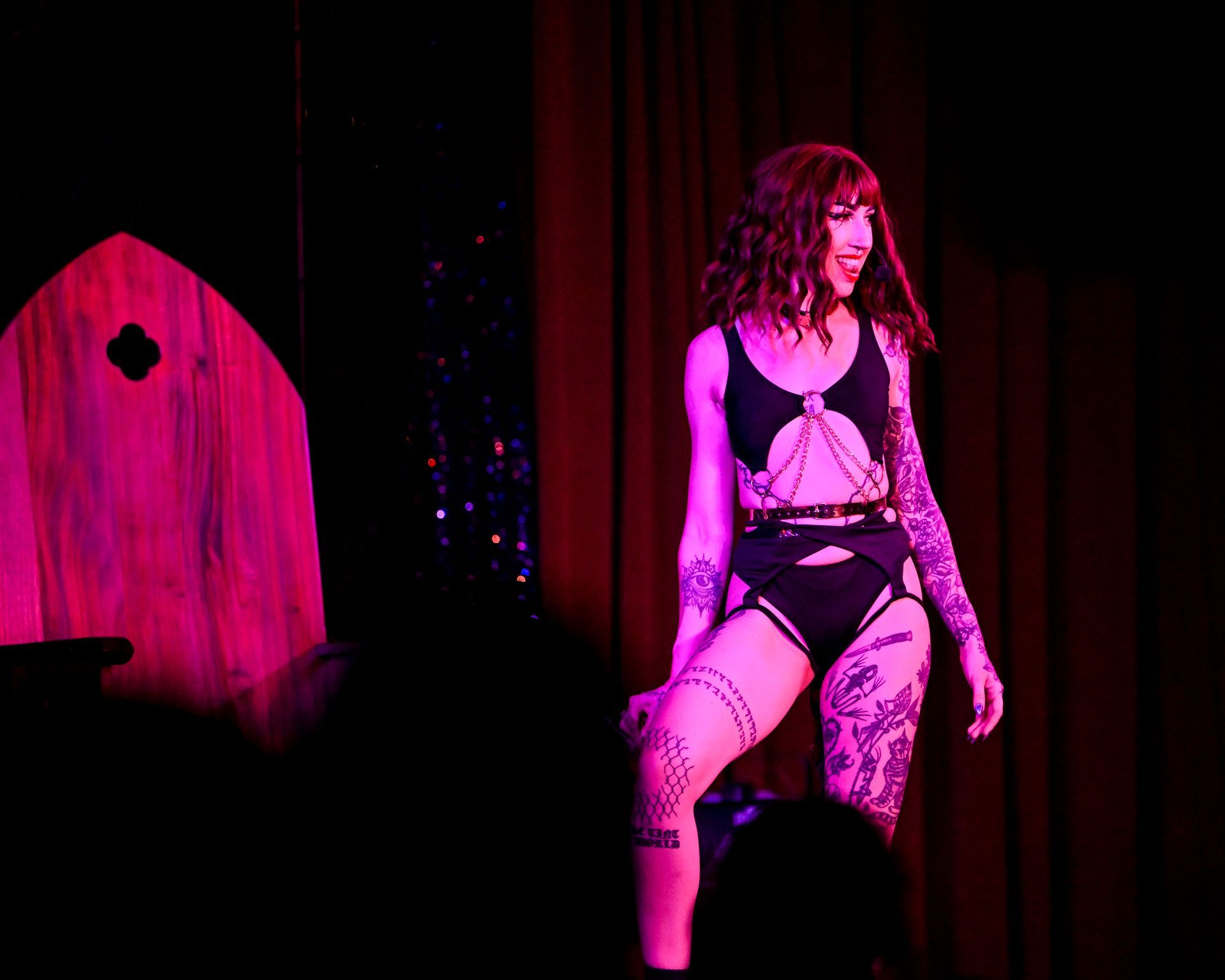 A woman is dancing on a stage with purple lights behind her— Lux Noir in Townsville City, QLD