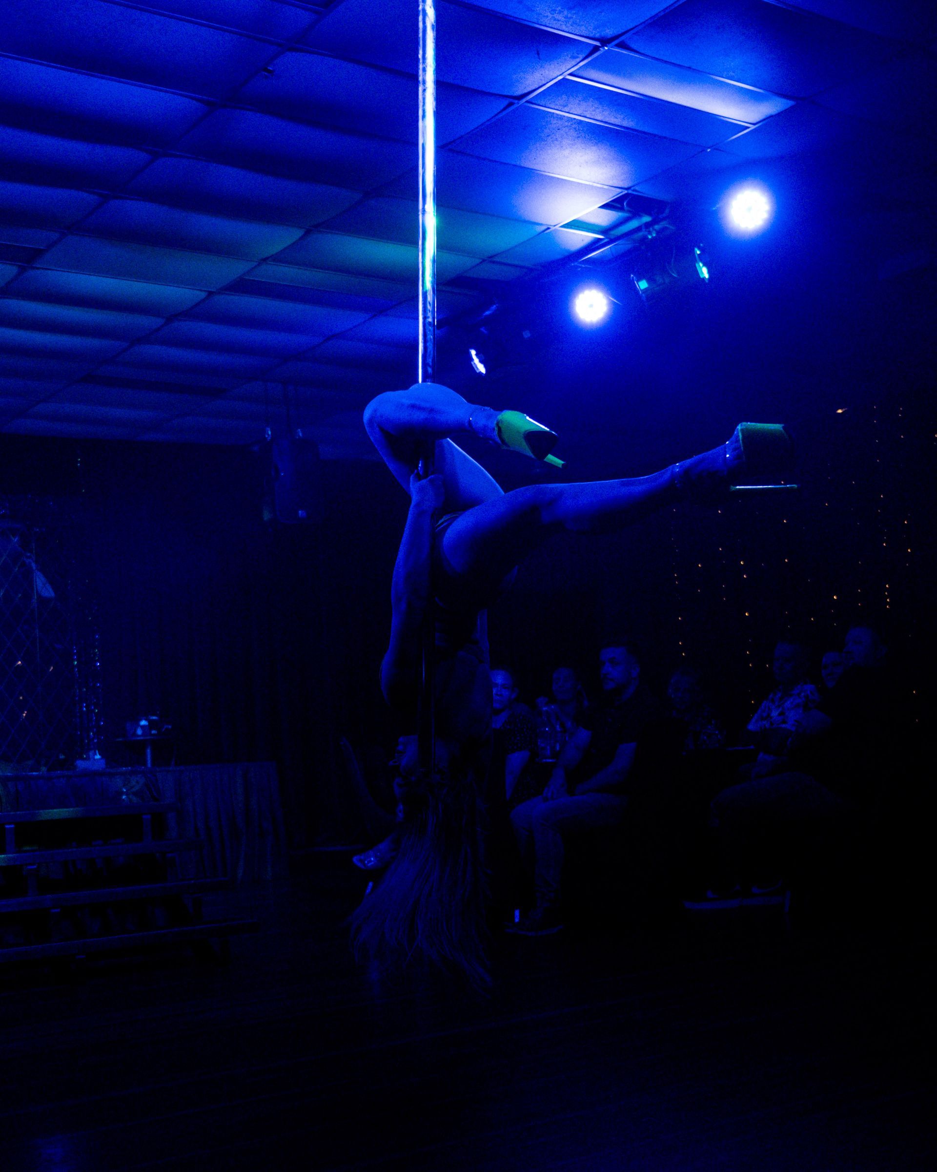 A woman is dancing on a pole in a dark room— Lux Noir in Townsville City, QLD