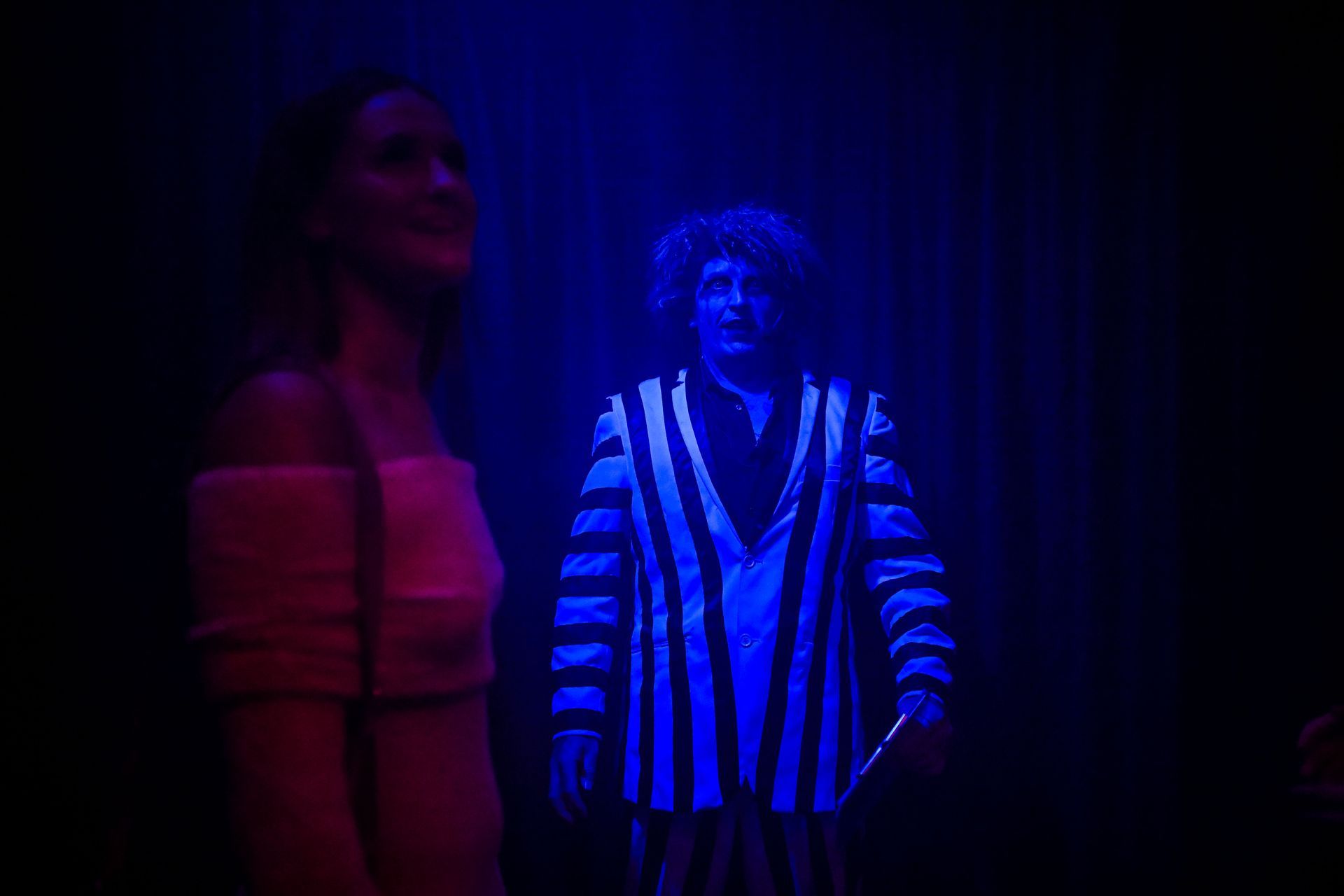 A woman is standing next to a man in a glow in the dark costume— Lux Noir in Townsville City, QLD