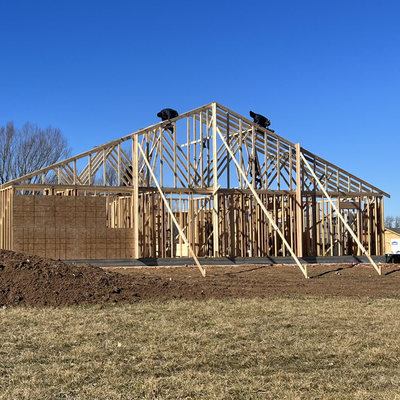 A house is being built in a field with a blue sky in the background.