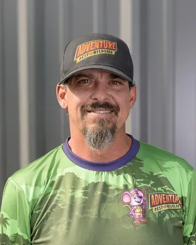 A man with a beard is wearing a hat and a green shirt.