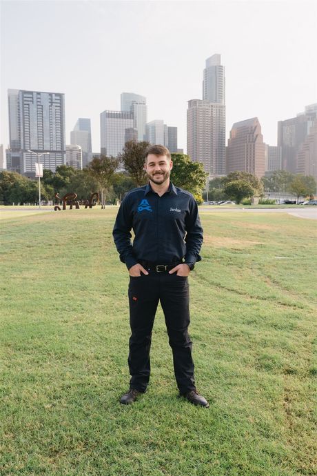 Man standing in front of a city skyline. He is wearing a dark shirt and black pants with his hands in his pockets. | Apex Mobile Autoworks