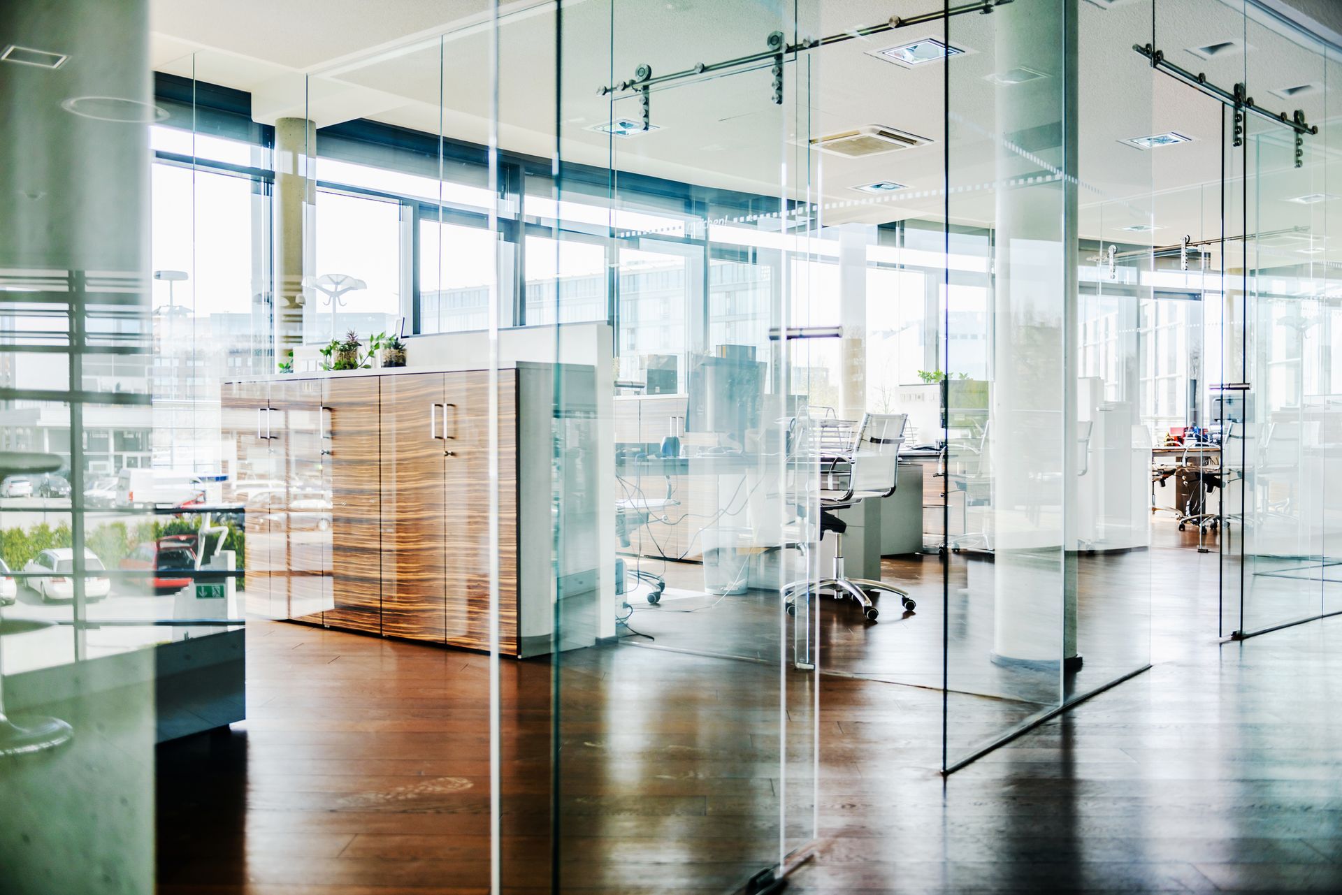 An office with a lot of glass doors and a wooden floor.