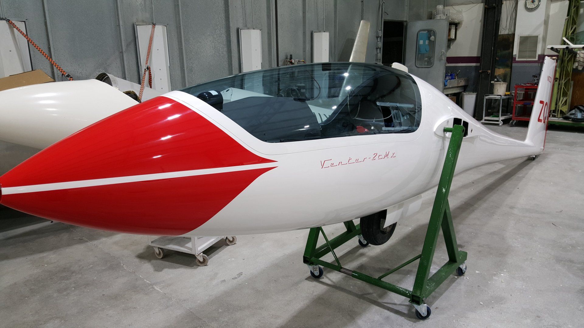 A red and white plane is sitting on a green stand