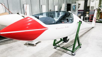 A red and white plane is sitting on a green stand