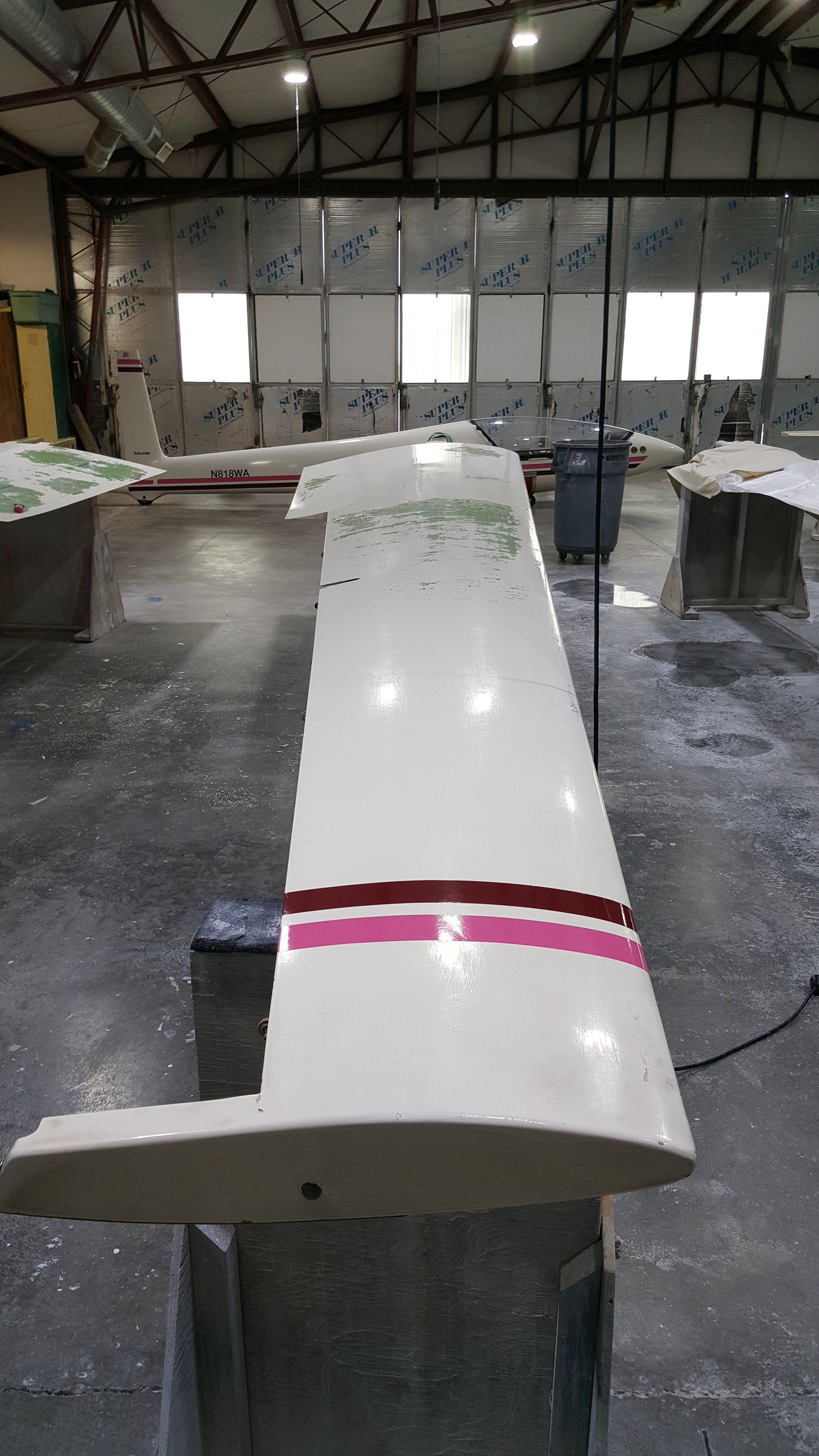 A white wing with a pink stripe on it is sitting in a warehouse.