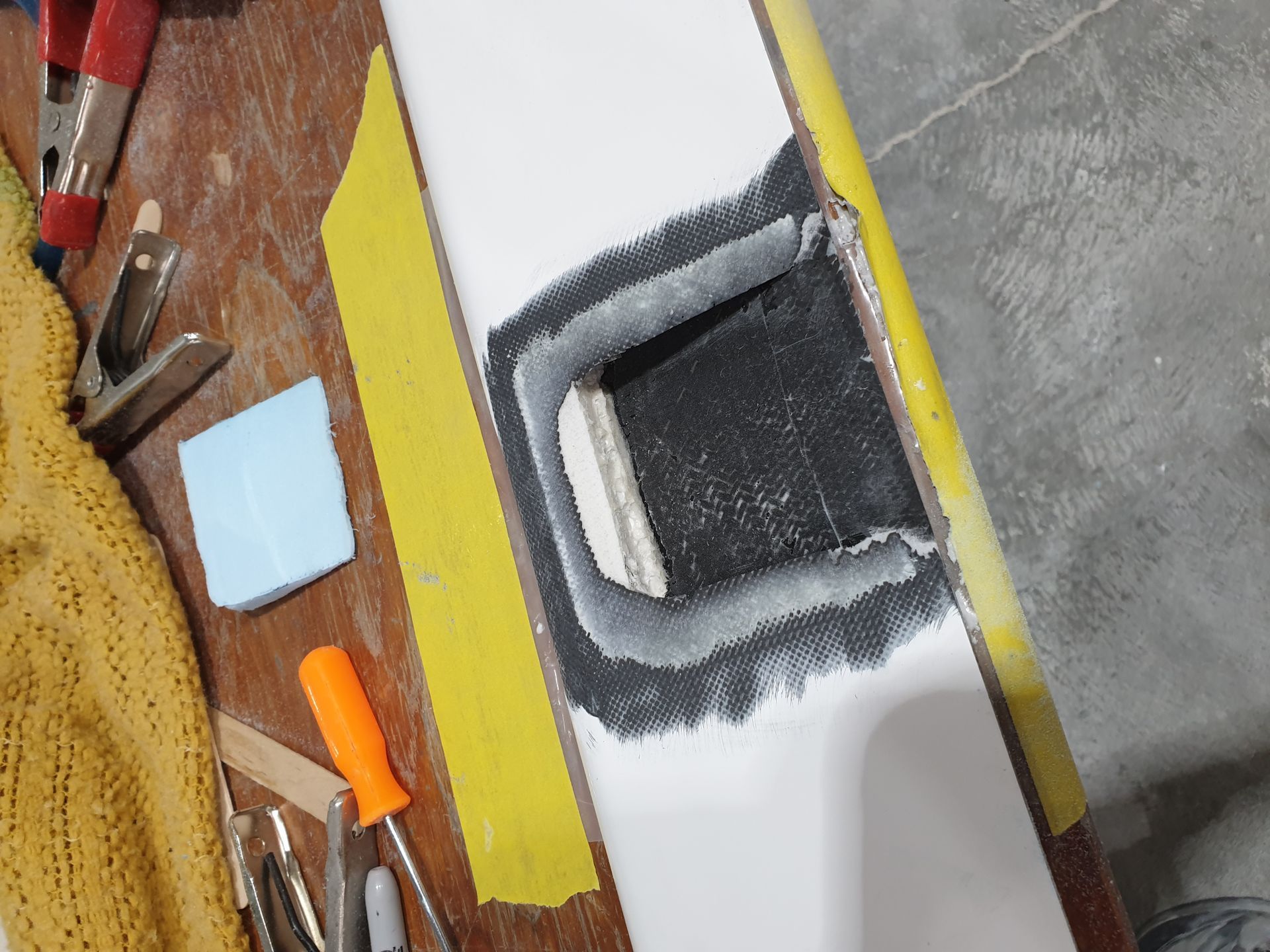 A piece of wood with a hole in it is sitting on a table with tools.