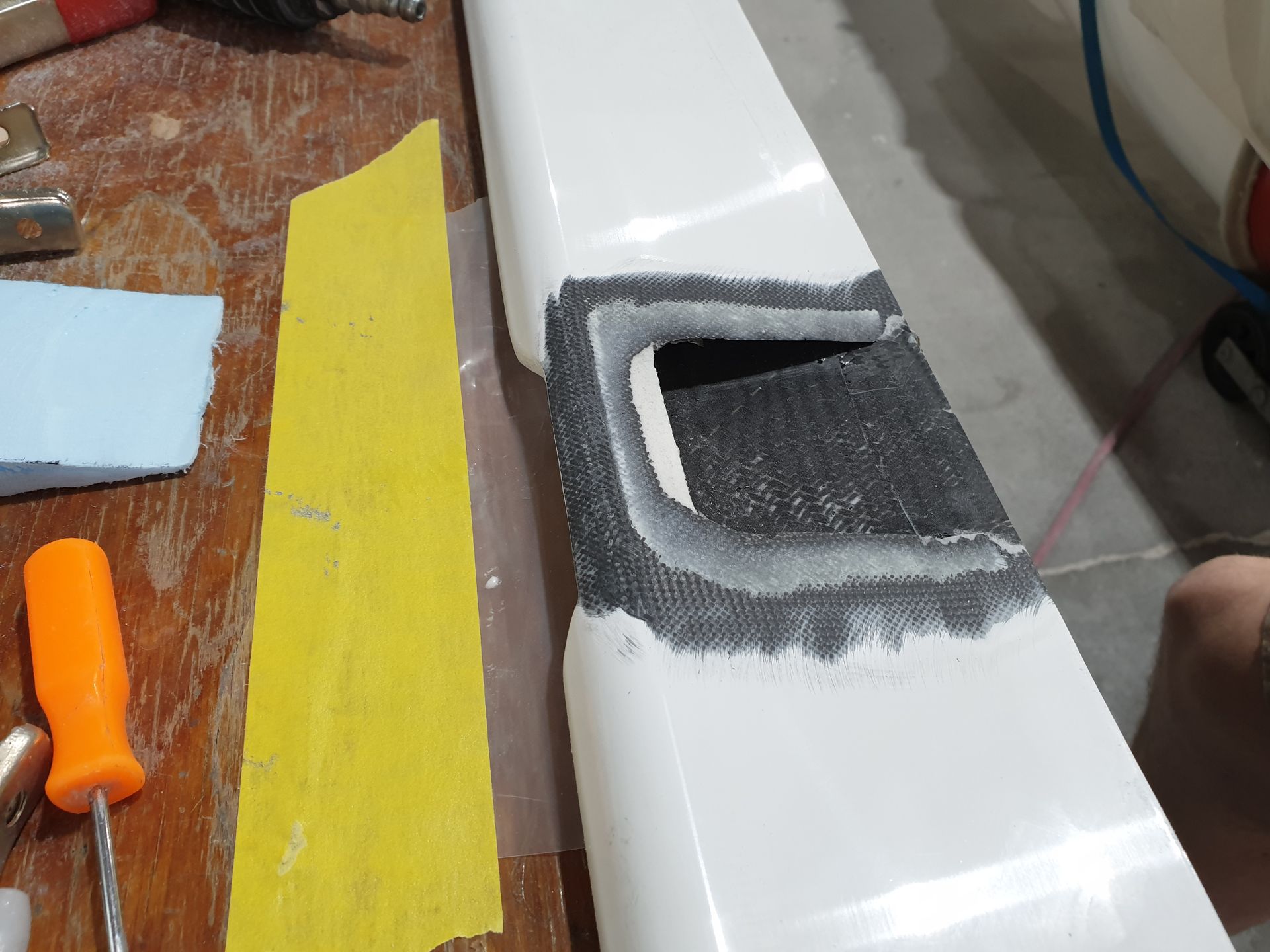 A person is working on a piece of plastic on a wooden table.