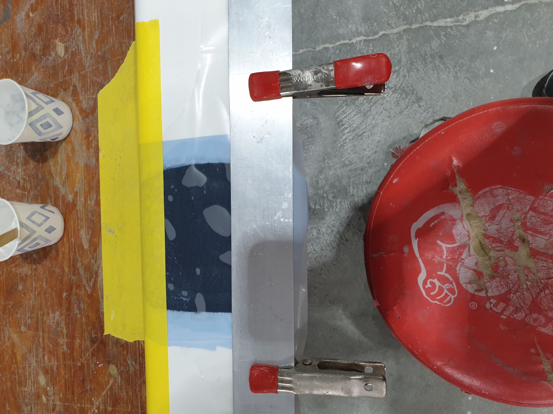 A person is standing next to a red bowl on a wooden floor.