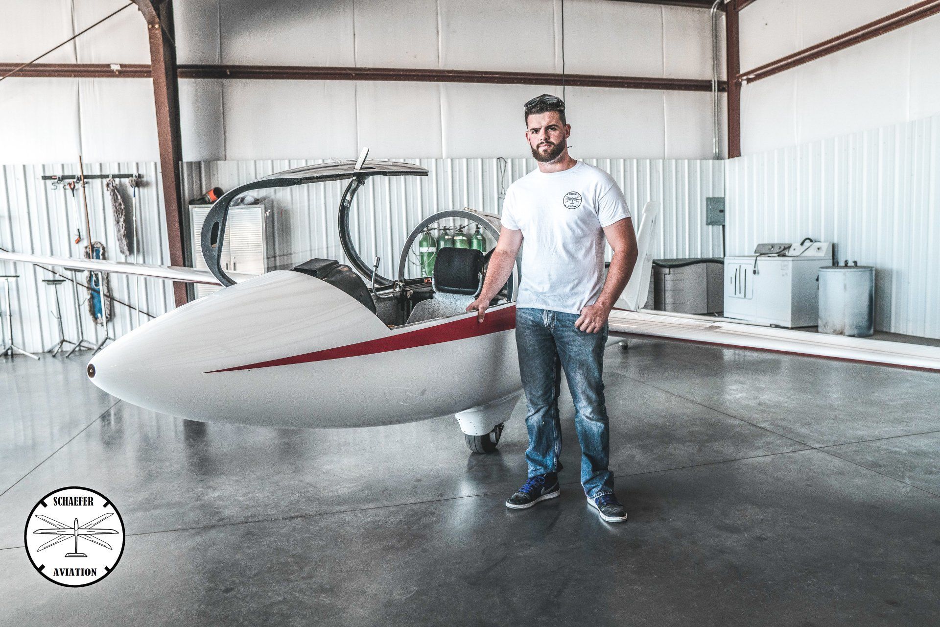 A man is standing next to a small plane in a hangar.