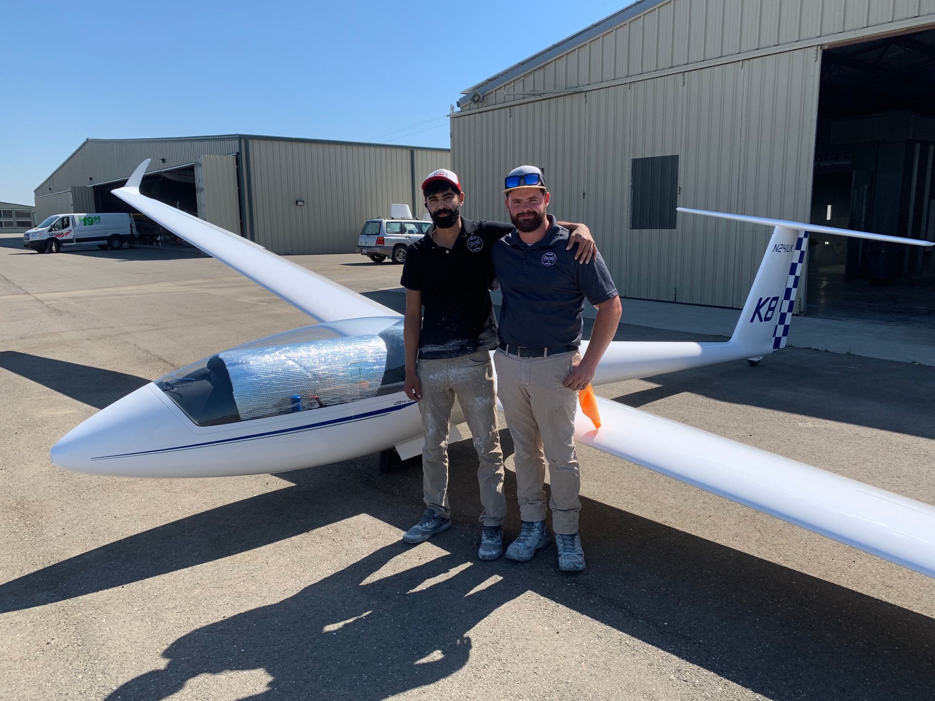 Two men are standing in front of a plane that says a33 on it