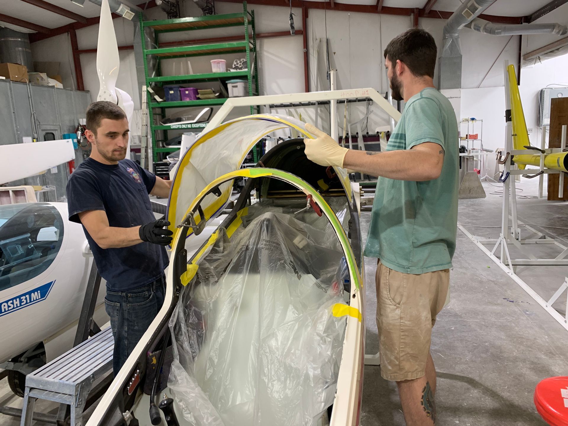 Two men are working on a plane in a factory.