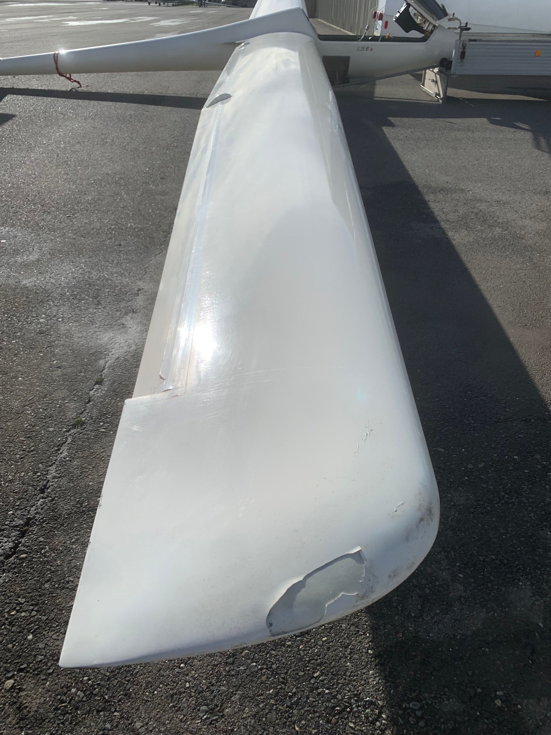 A white object is sitting on the ground next to a plane.