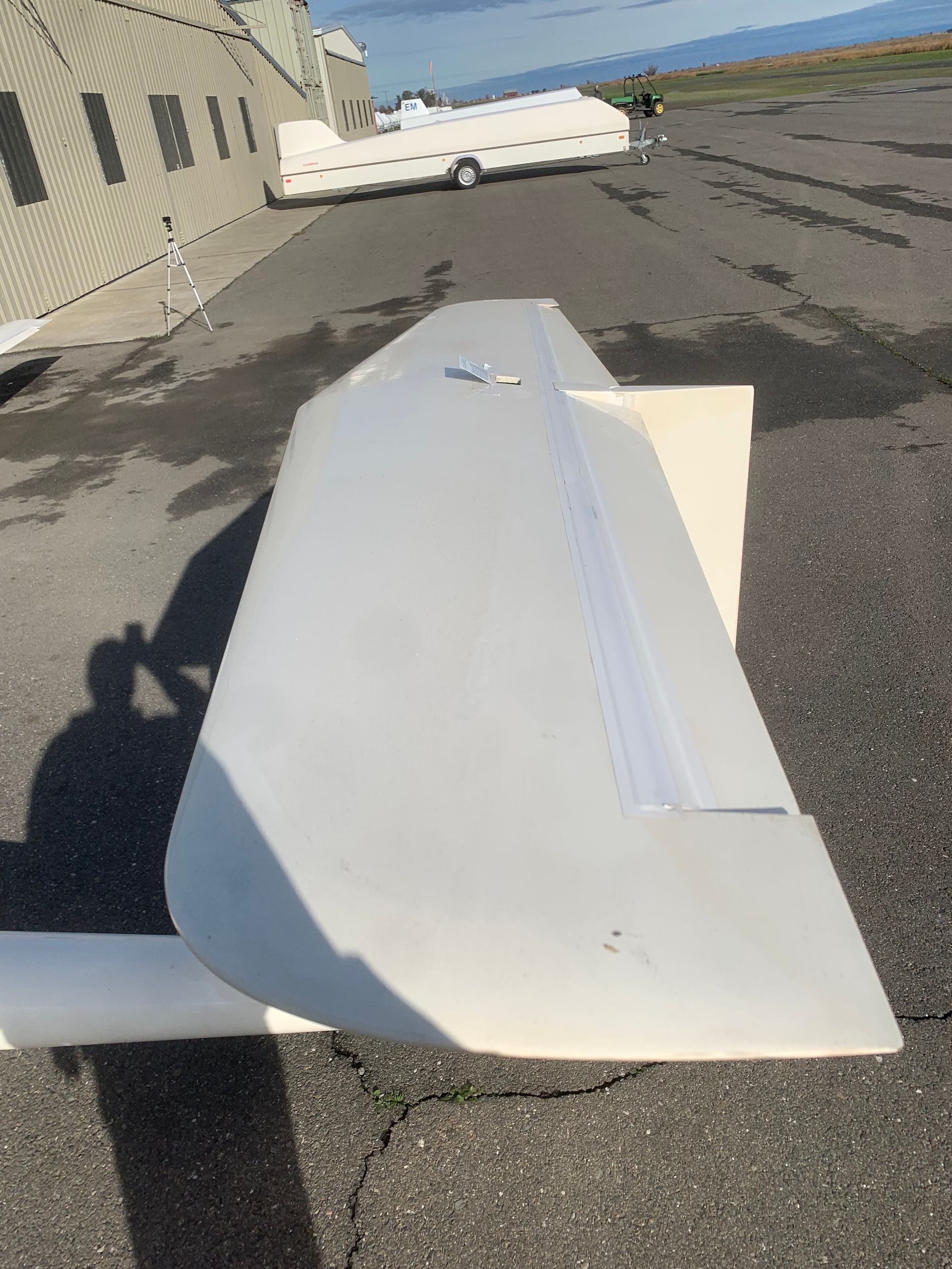 A plane wing is sitting on the ground in front of a building.