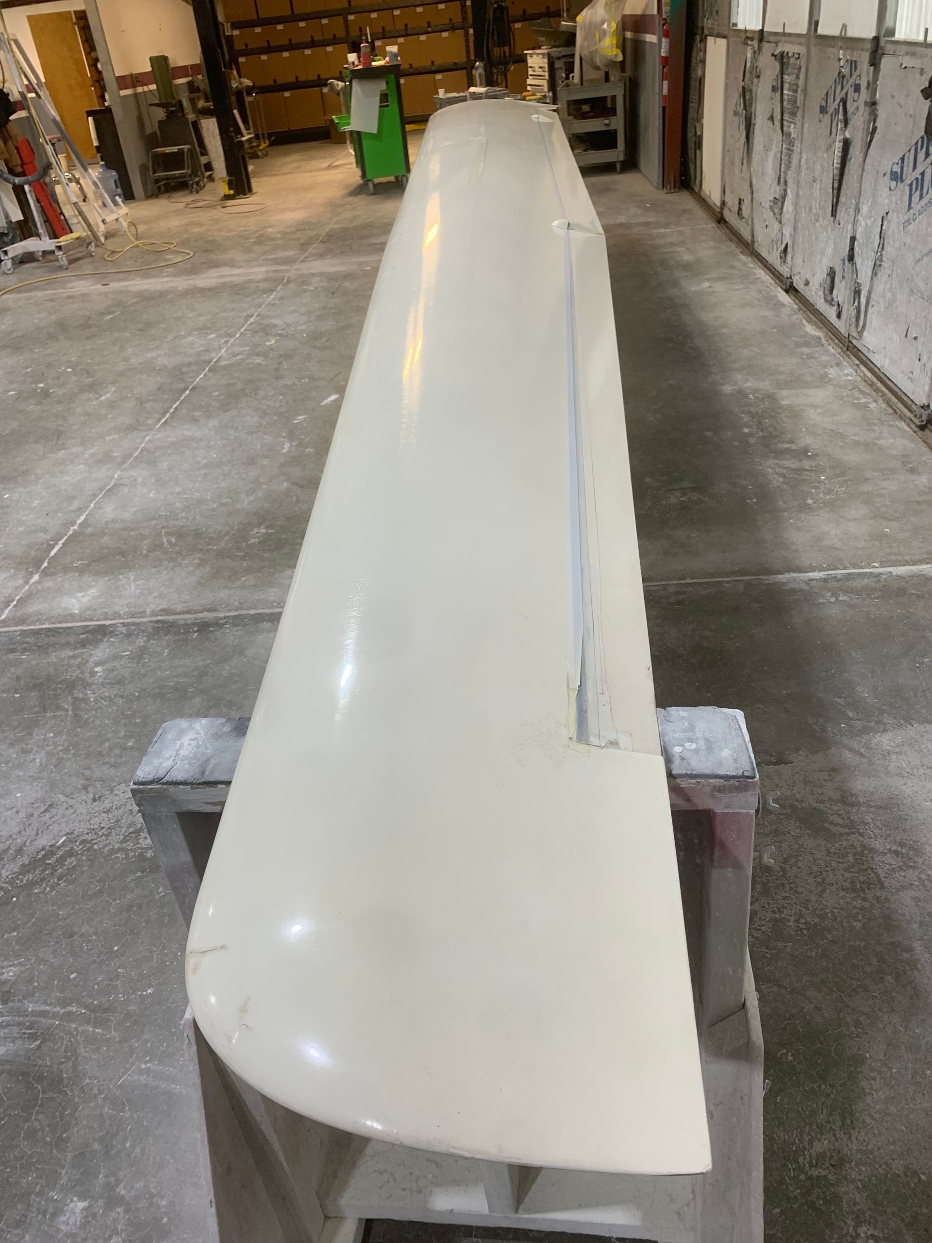 A long white object is sitting on a concrete surface in a room.