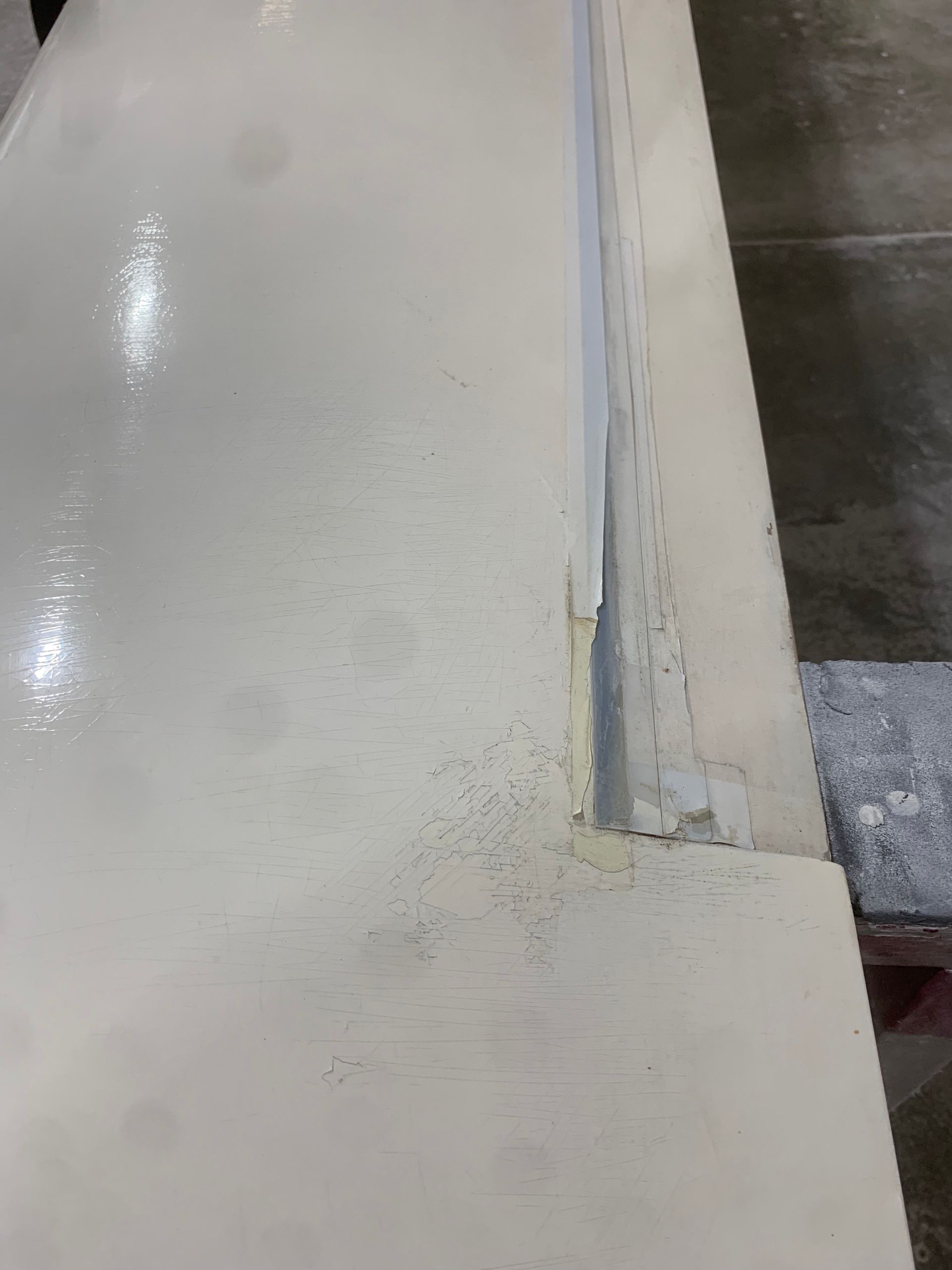 A close up of a white concrete floor with a corner missing.