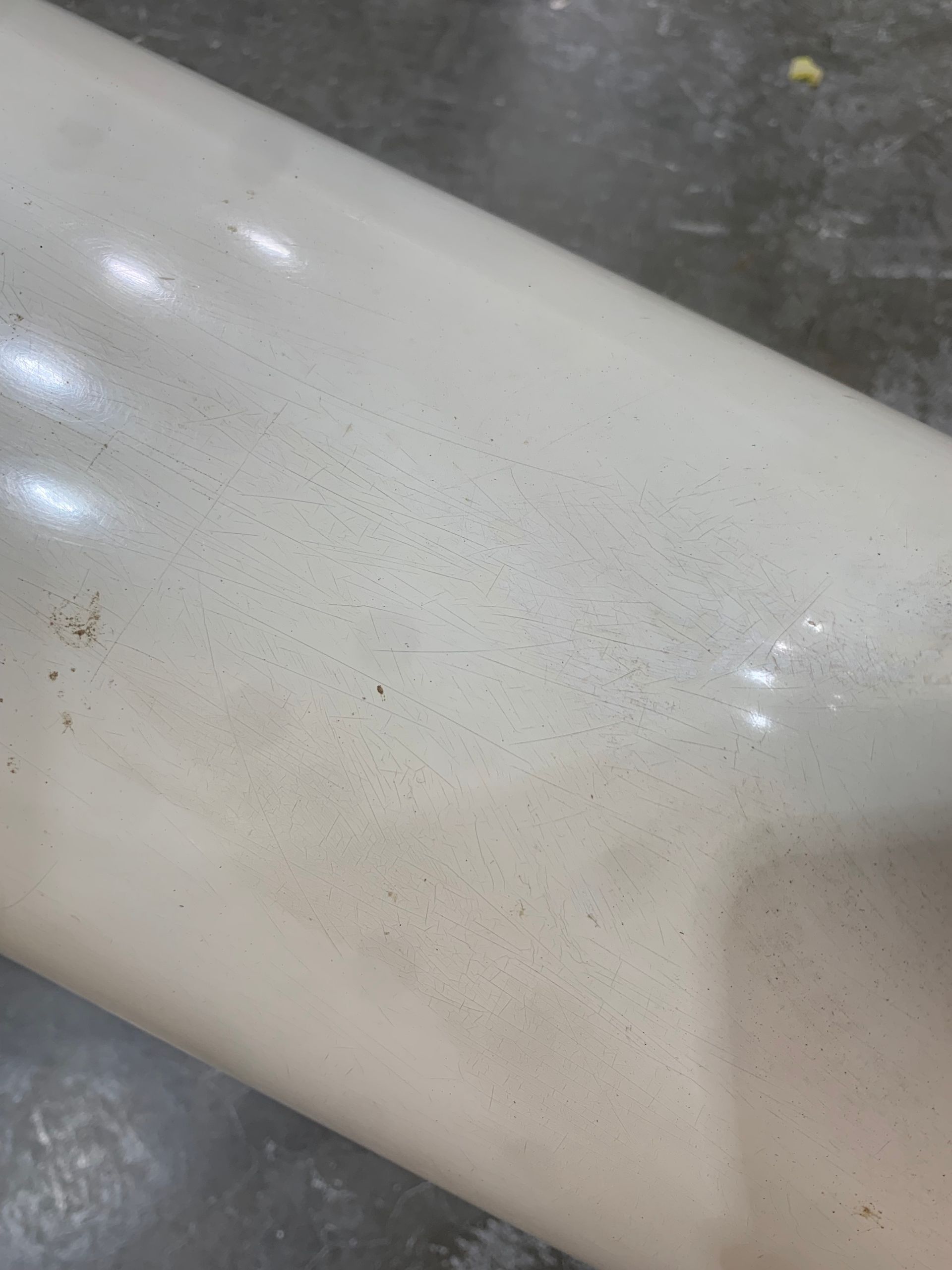 A close up of a white pipe on a concrete surface.