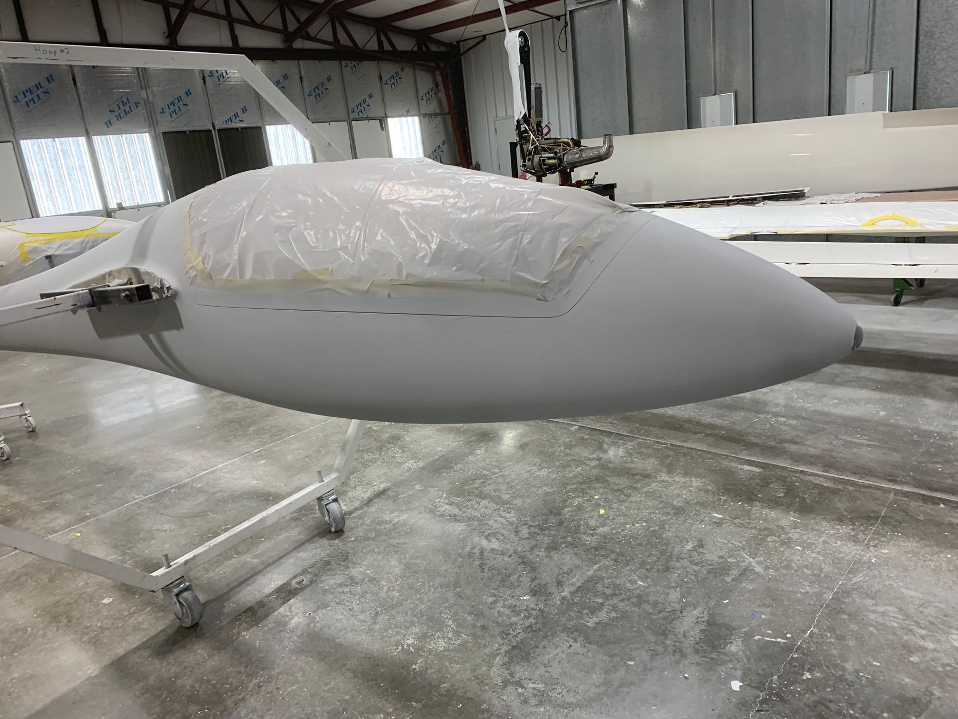 A gray airplane is sitting on a concrete floor in a hangar.