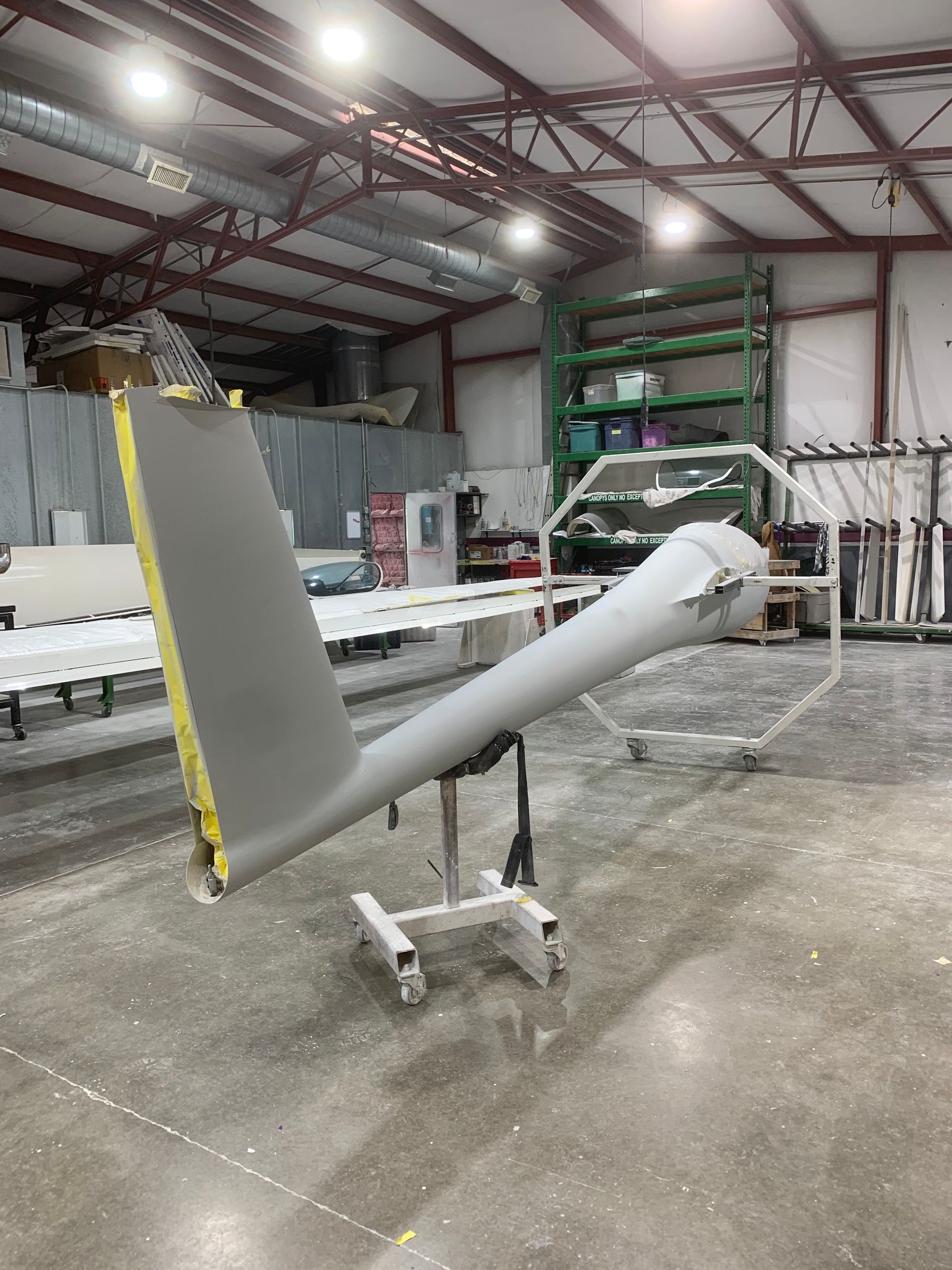 An airplane wing is sitting on a stand in a warehouse