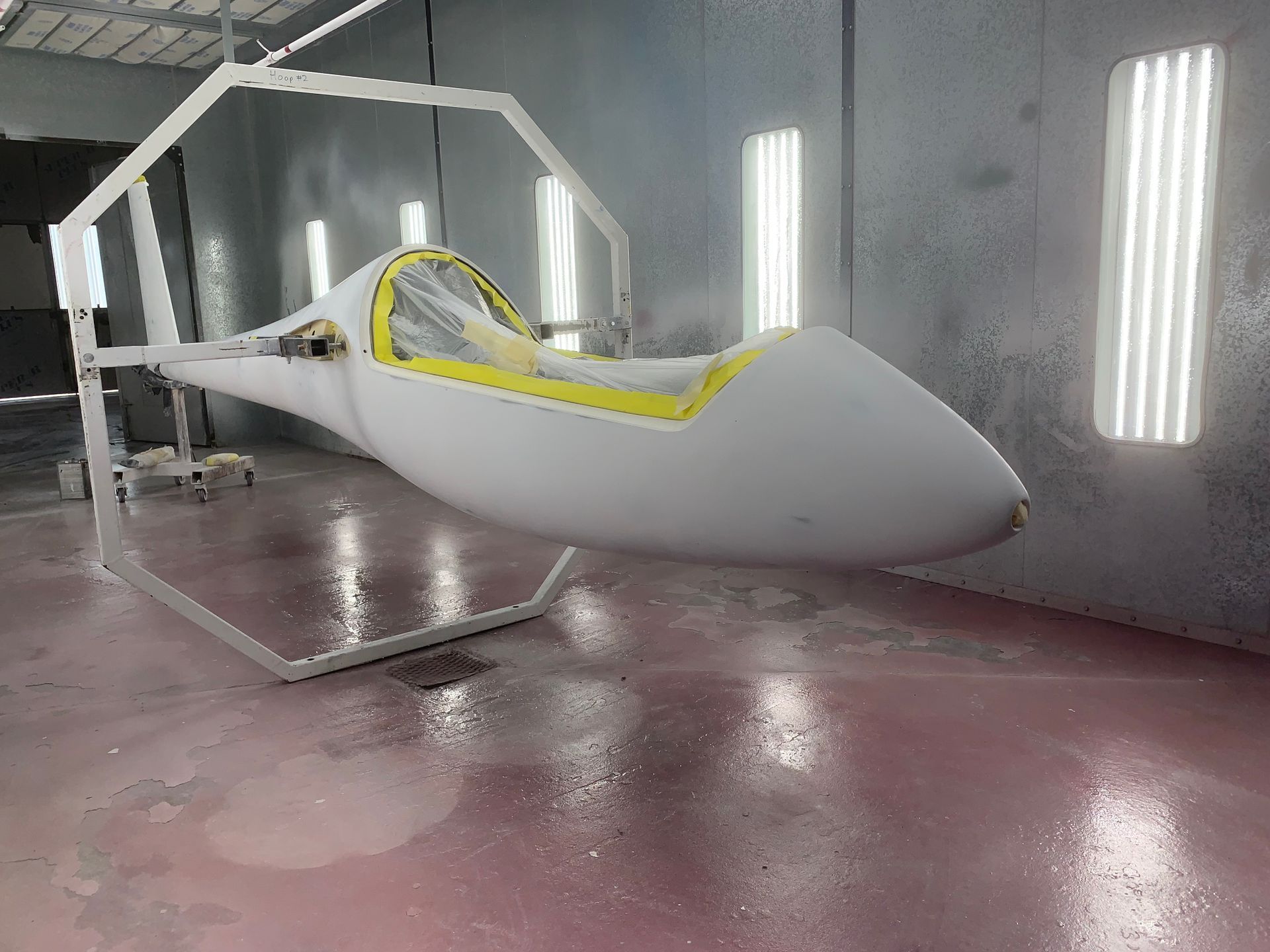A white plane is sitting on a stand in a paint booth.