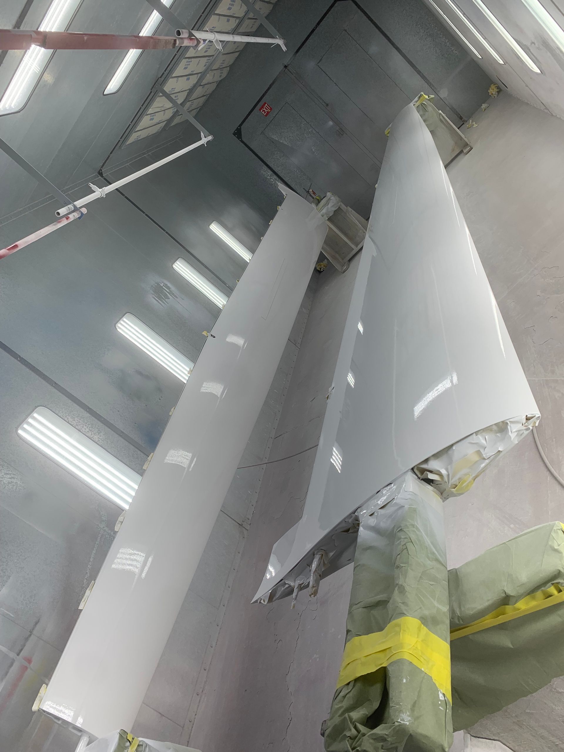 A plane wing is being painted in a paint booth.