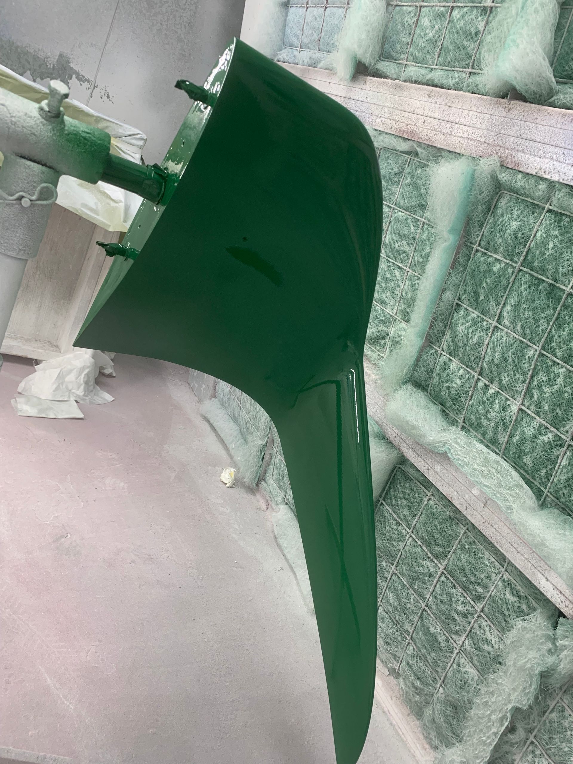 A green umbrella is hanging from a pole in a room.