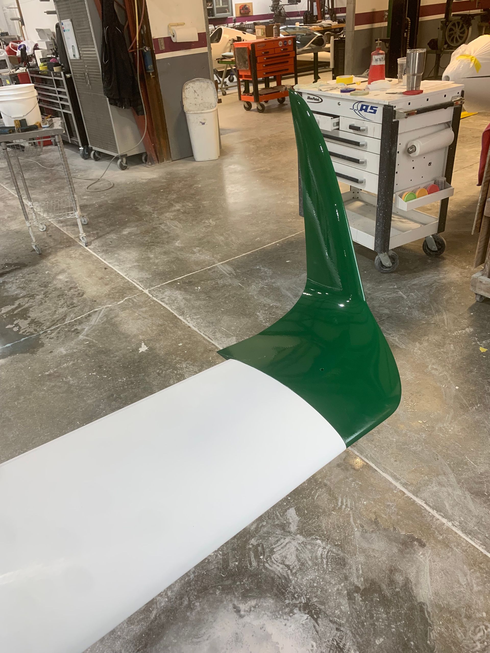 A green and white object is sitting on a concrete floor in a room.