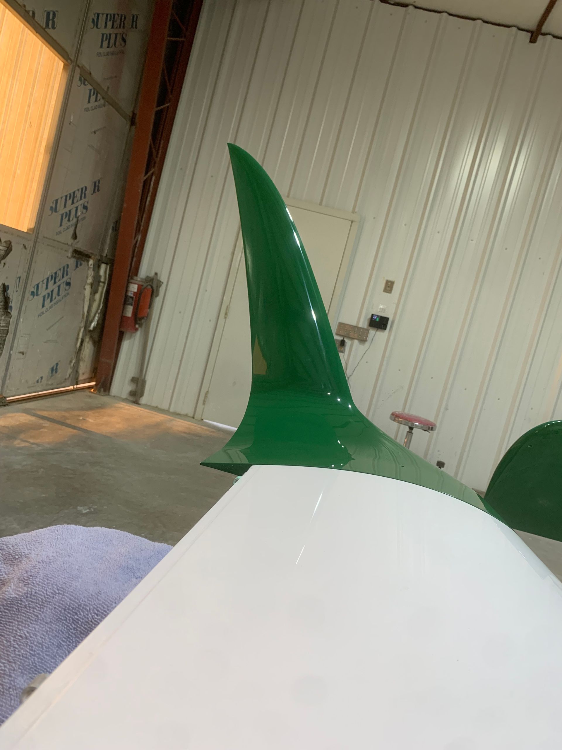 A green shark fin is painted on a white plane