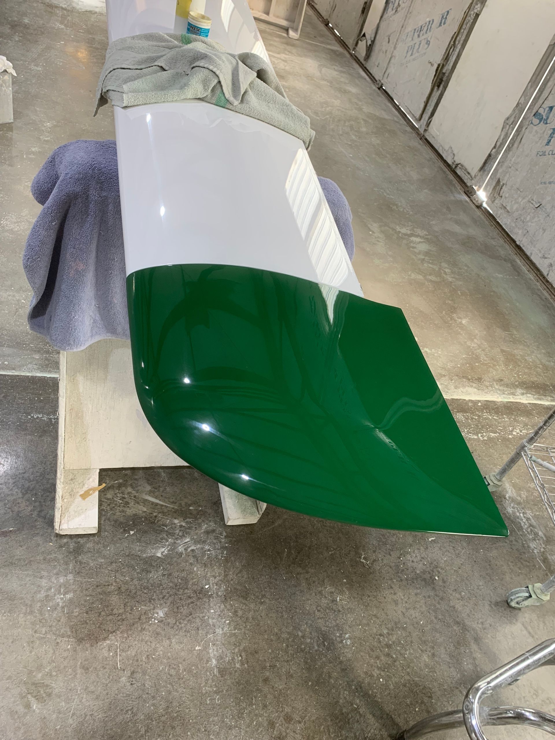 A green and white object is sitting on a concrete floor.